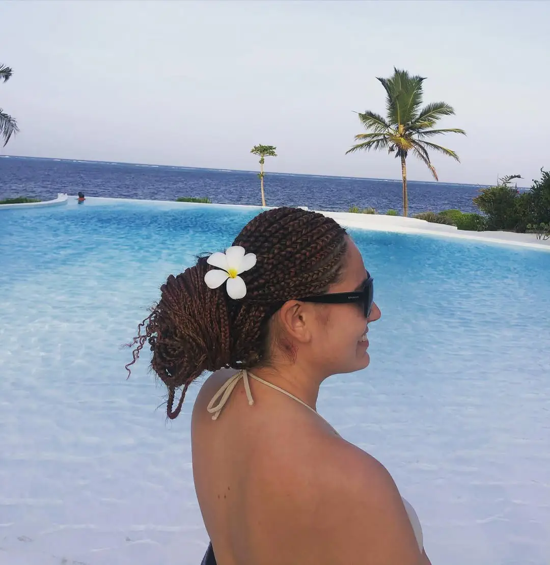 22 Refreshing Hairstyles for Swimming: Stylish Looks That Stay Put in the Water 22 Braided Low Bun with Frangipani Flower Accent